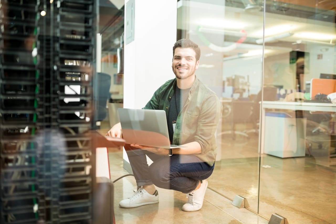 Engineer with a laptop beside the server rack