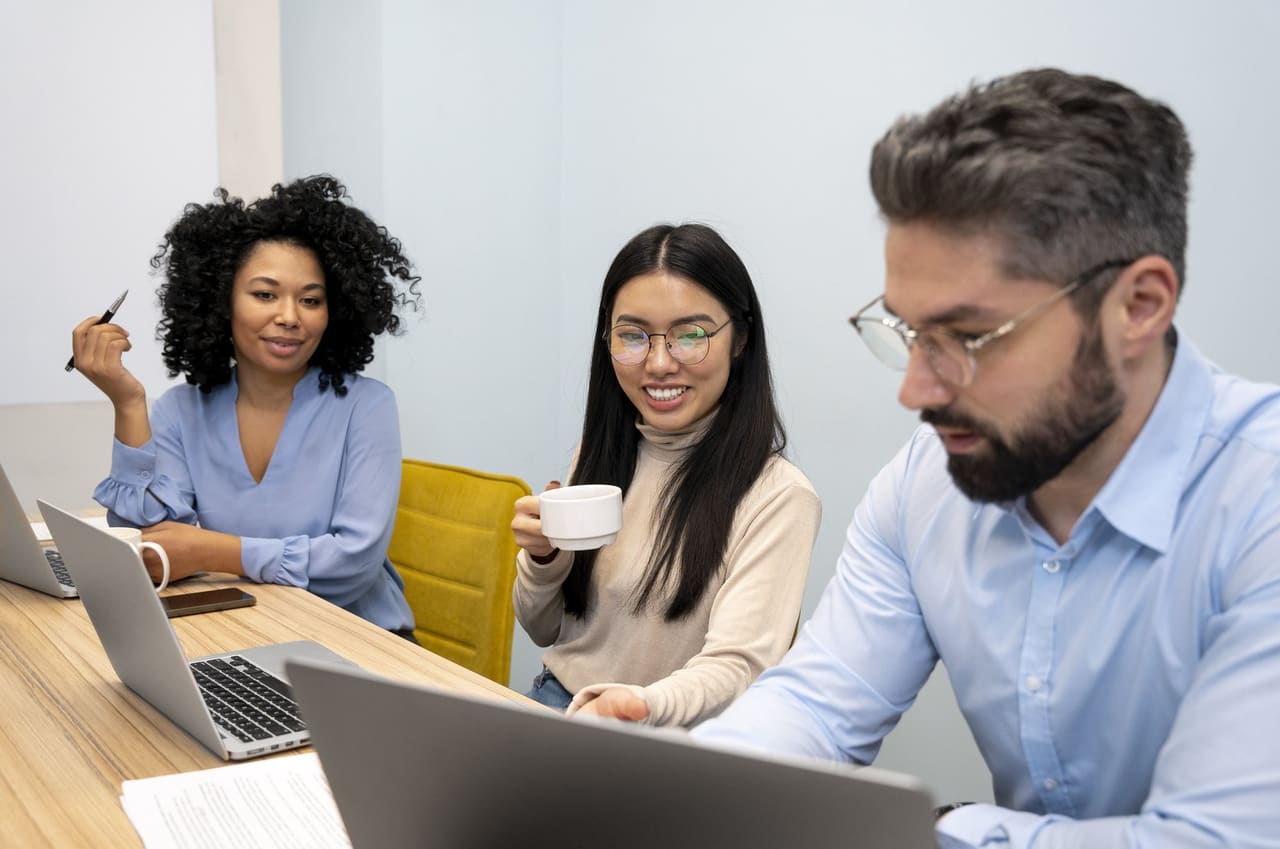 Three colleagues work together around their laptops